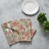 Elegant place setting with two tan and pink floral napkins and silverware arranged creatively.