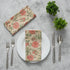 Elegant place setting with two pink and tan floral napkins and silverware arranged creatively.