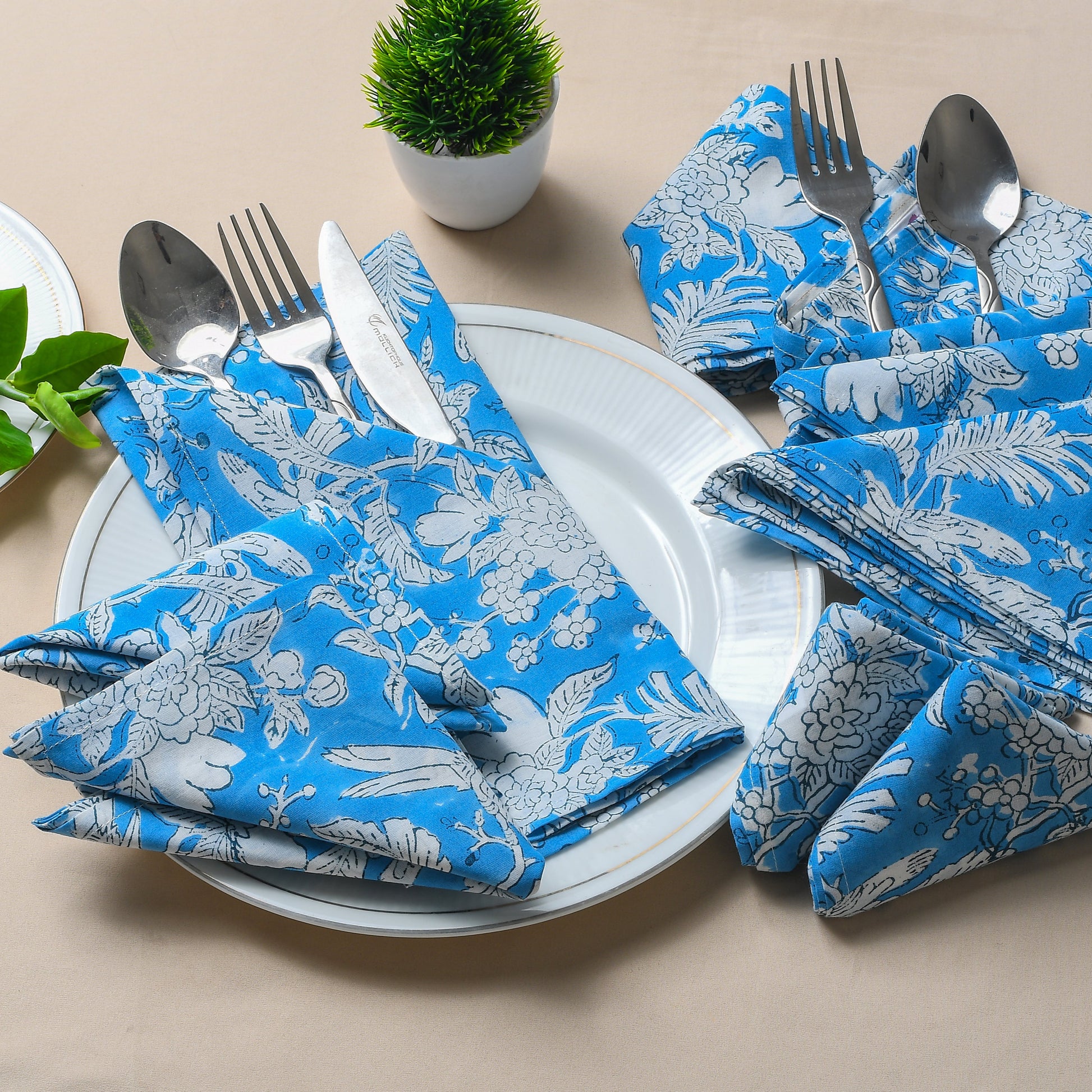 Elegant place setting with two blue floral napkins and silverware arranged creatively.
