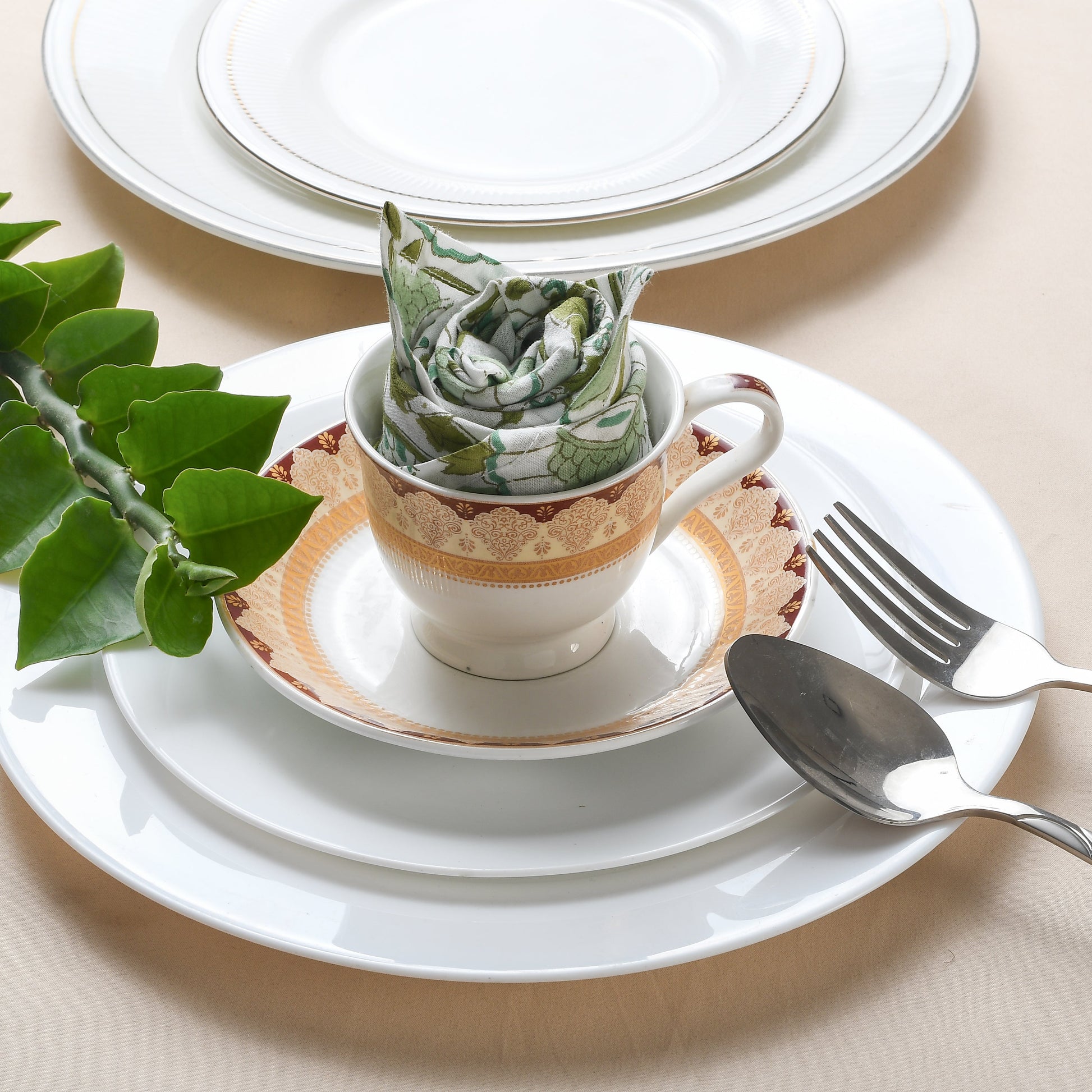 Rolled floral napkin placed upright on a white plate with silverware.