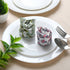 Rolled floral napkin placed on white plate with green leaf decoration.