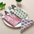 Red floral block-printed napkin laid flat on white background.