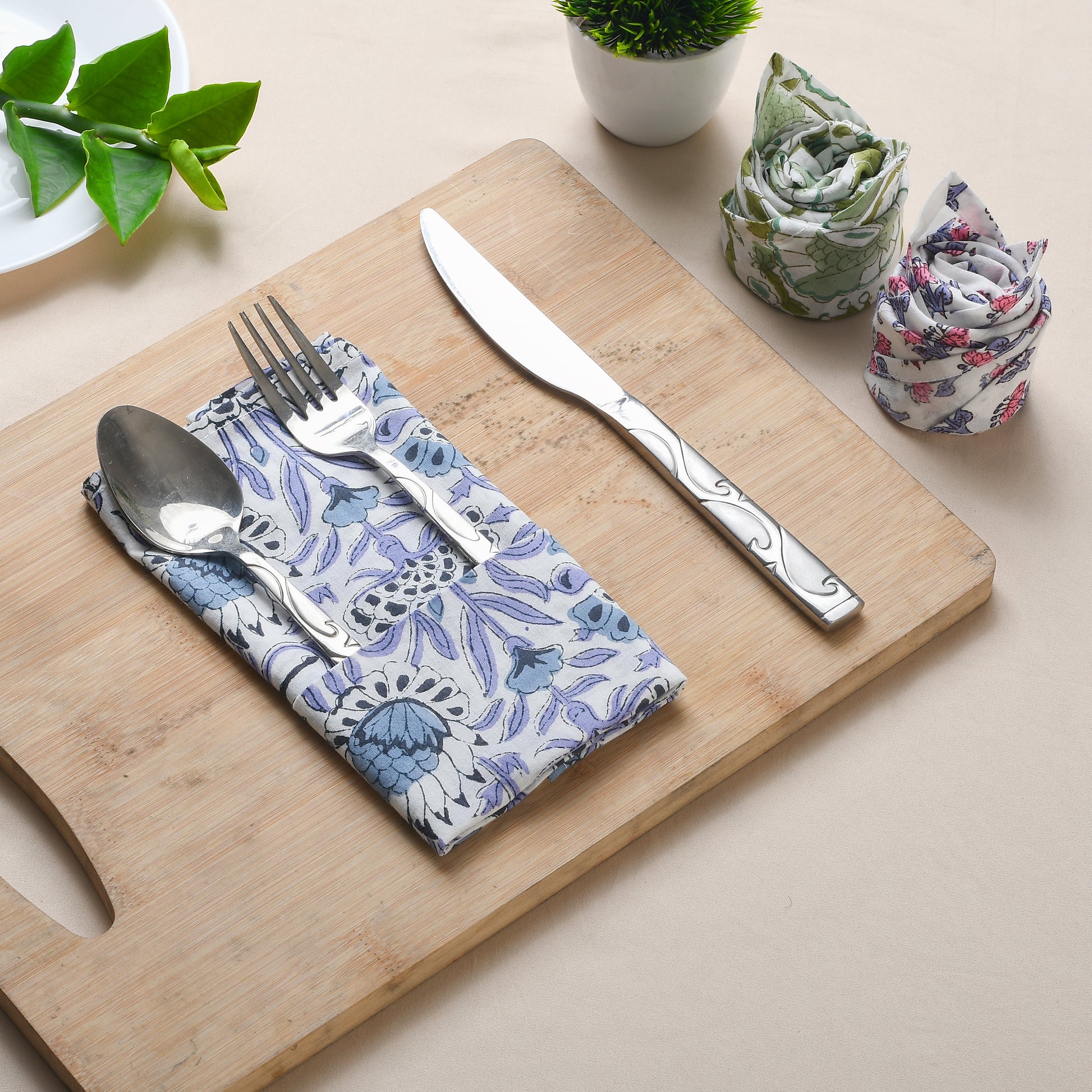 Blue block print napkin folded on tray with silverware and rolled matching napkin.