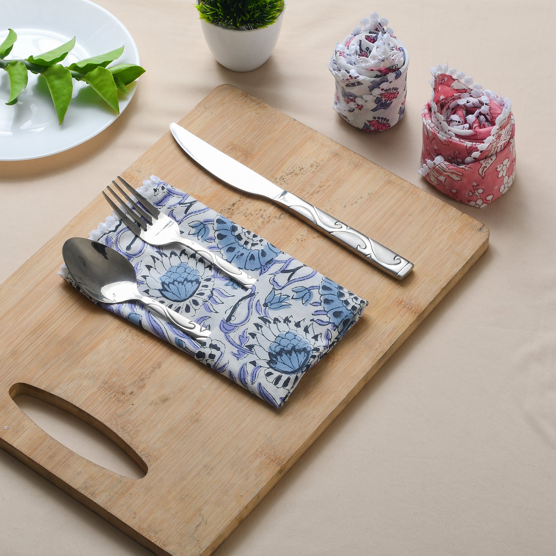 Blue floral napkin folded with silverware on a wooden serving tray.