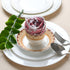 Rolled multicolor napkin on white plate with green foliage and fork.