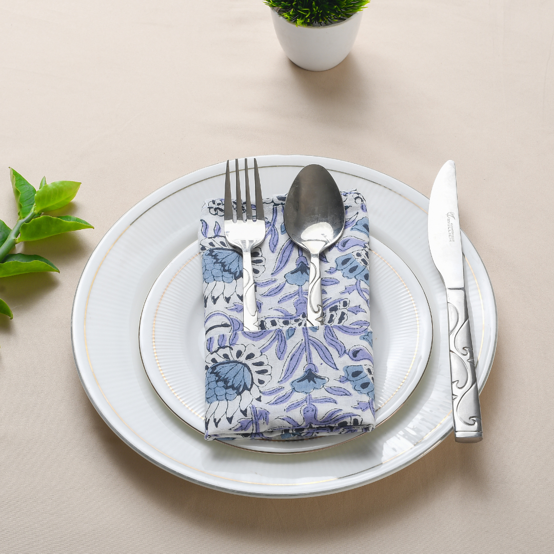 Blue floral napkin with plate and cup in flat lay setting.