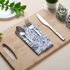 Blue floral napkin folded with silverware on a wooden serving tray.