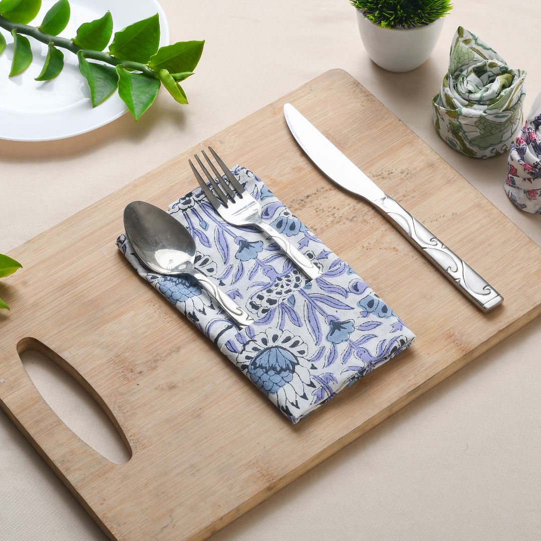 Blue floral napkin folded with silverware on a wooden serving tray.