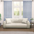 A pair of semi-sheer blue cotton block print curtains hanging in a room with a light coming through, showcasing a boho-chic design.