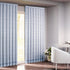A pair of semi-sheer blue cotton block print curtains hanging in a room with a light coming through, showcasing a boho-chic design.