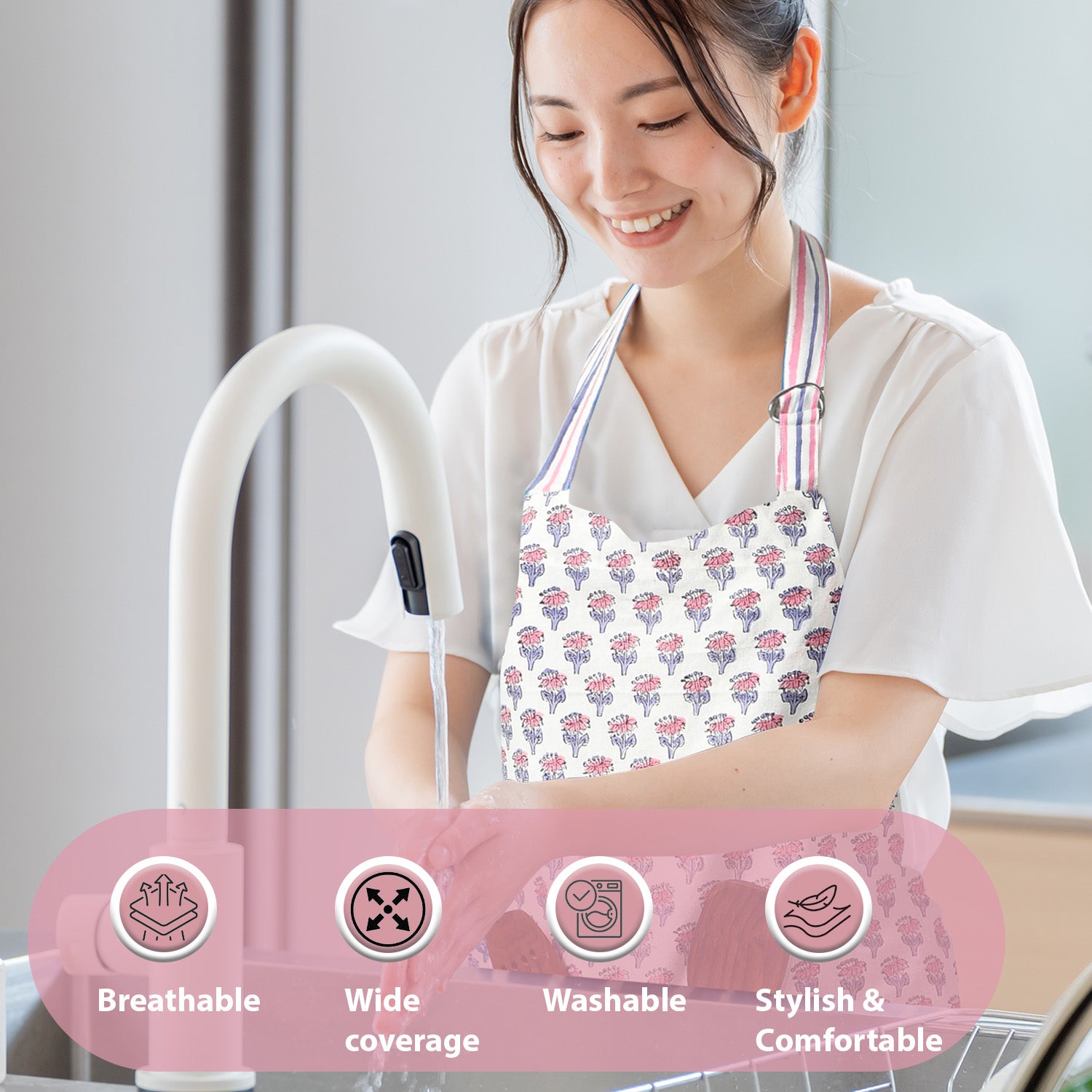 lady washing dishes and wearing a pink and white floral block print apron thats breathable, has wide coverage, washable, and stylish and comfortable