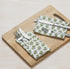 green floral napkin placed under silverware on wooden serving tray, with matching napkins rolled beside.