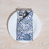 Single blue floral napkin wrapped around silverware on a white plate.