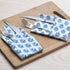 Blue floral napkin placed under silverware on wooden serving tray, with matching napkins rolled beside.