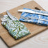 Blue and green floral napkins folded with silverware on a wooden serving tray.