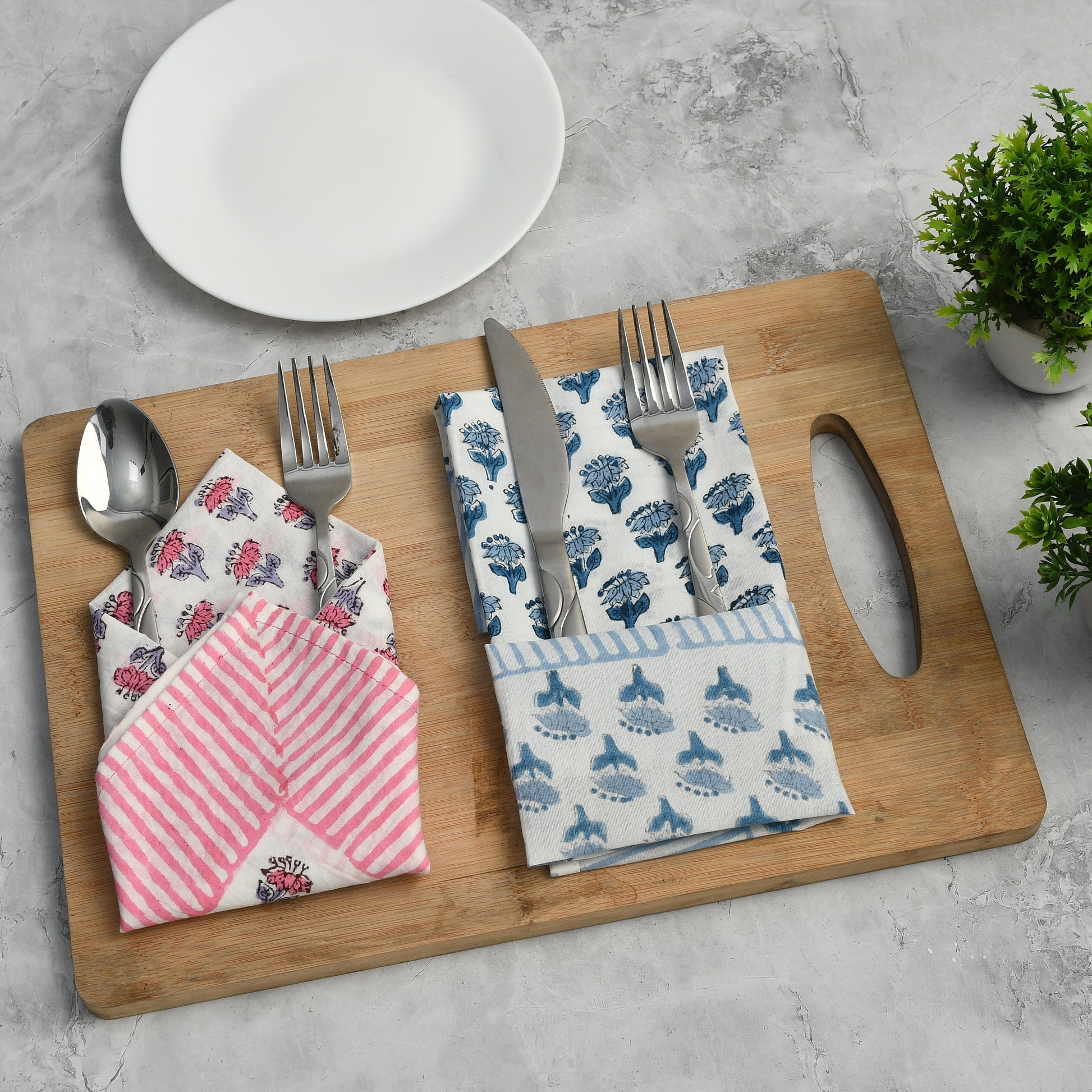 Blue floral napkin folded with silverware on a wooden serving tray.