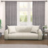 Semi-sheer cotton block print curtains in gray with intricate patterns, hanging in a room with a light source behind them, showcasing their transparent quality and rod pocket design.