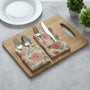 tan and pink floral napkin placed under silverware on wooden serving tray, with matching napkins rolled beside.