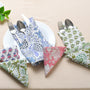 A set of cotton cloth napkins in various floral and geometric prints, displayed on a table with cutlery.