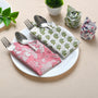Four napkins in floral prints folded with silverware in pink and green tones.

