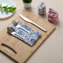 Blue floral napkin folded with silverware on a wooden serving tray.

