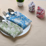 Blue block print napkin folded on tray with silverware and rolled matching napkin.


