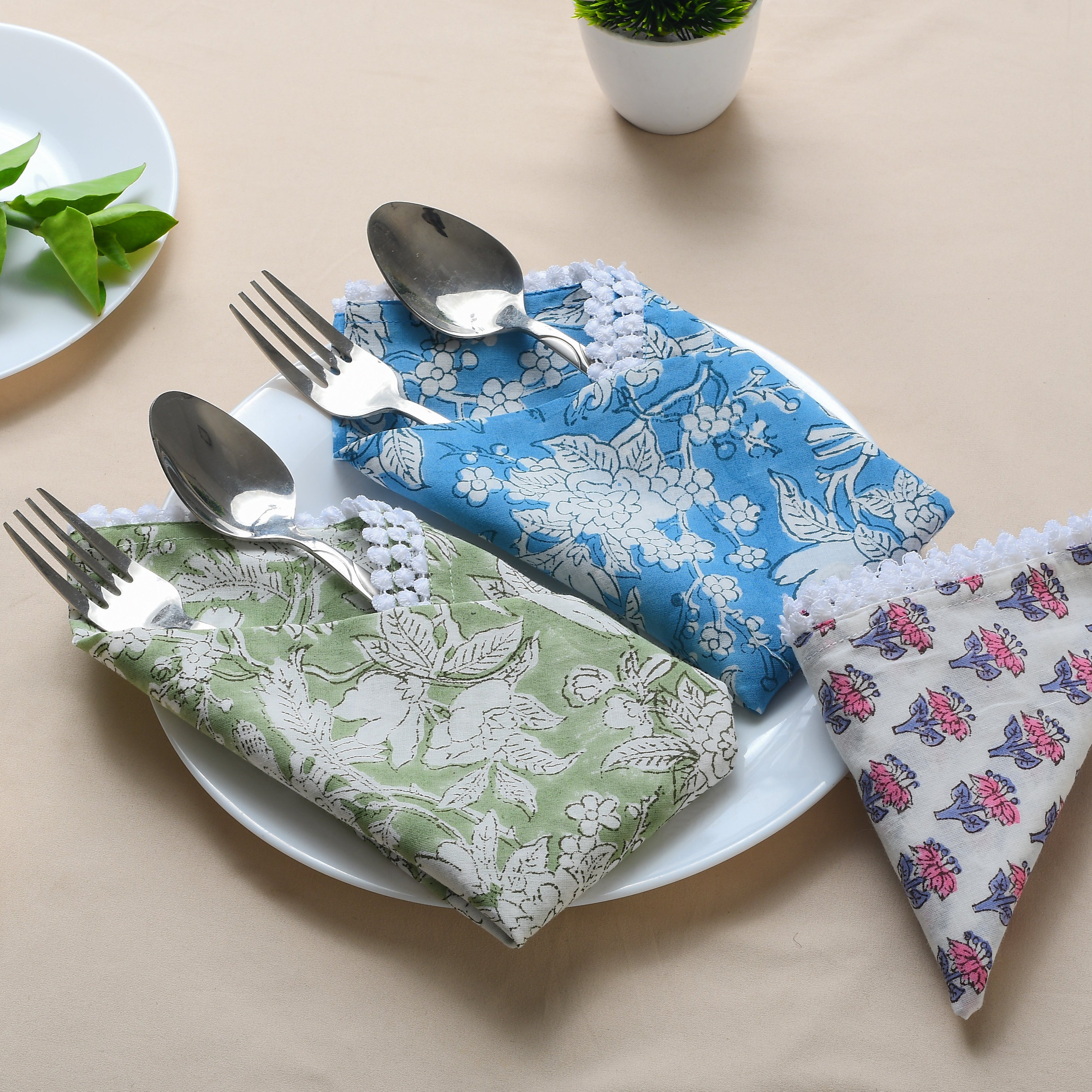 Place setting with assorted napkins and rolled versions on a white plate.

