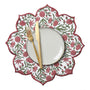 floral green and red placemat layered under white ceramic dishes