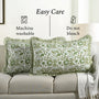 Green patterned pillows on a beige sofa with care instructions displayed.