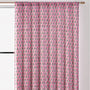 Semi-sheer cotton block print curtains in poppy pink with intricate patterns, hanging in a room with a light filtering through.