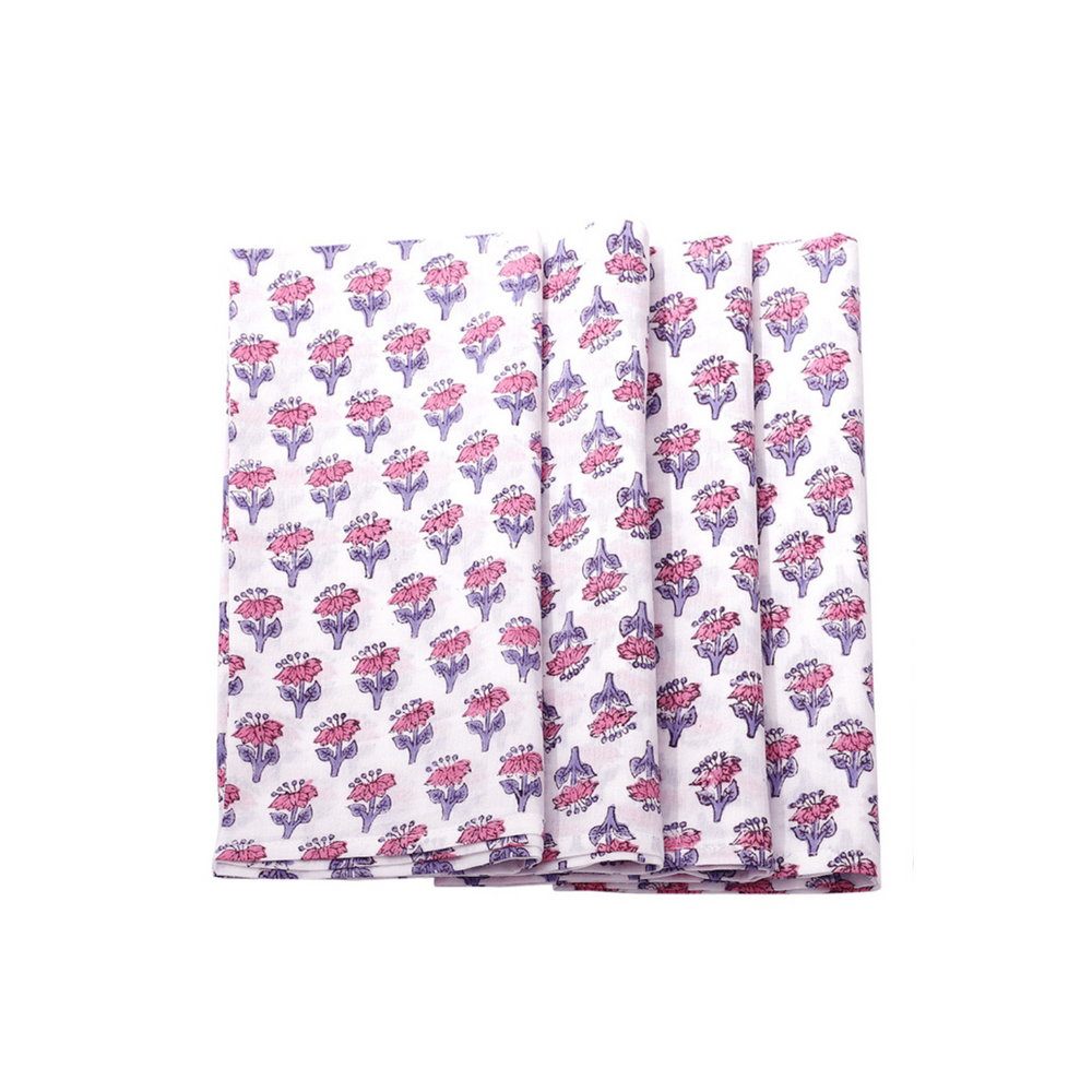 A set of folded cotton cloth napkins with a hand-printed floral and geometric design in pink and purple colors on a white background.