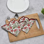 green and red floral placemat layered under white ceramic dishes