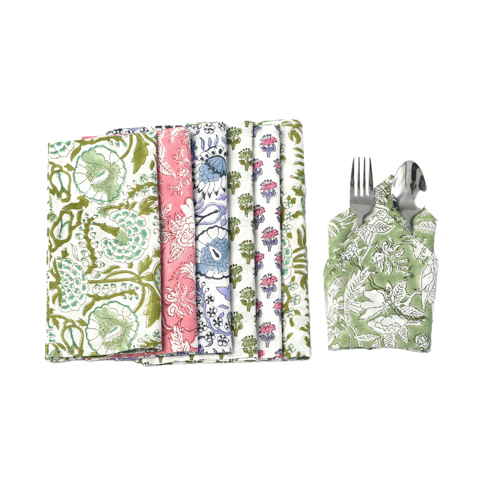 Flat lay of five assorted napkins with one folded and wrapped around silverware.


