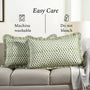 Green patterned pillows on a beige sofa with care instructions displayed.