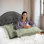 Woman sitting on a bed with green patterned pillows