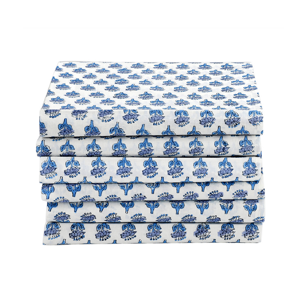 Stack of neatly folded blue floral napkins on a white background.

