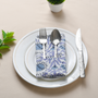 Blue floral napkin with plate and cup in flat lay setting.

