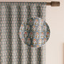 Semi-sheer cotton block print curtains in gray with intricate patterns, hanging in a room with a light source behind them, showcasing their transparent quality and rod pocket design.