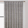 Semi-sheer cotton block print curtains in gray with intricate patterns, hanging in a room with a light source behind them, showcasing their transparent quality and rod pocket design.