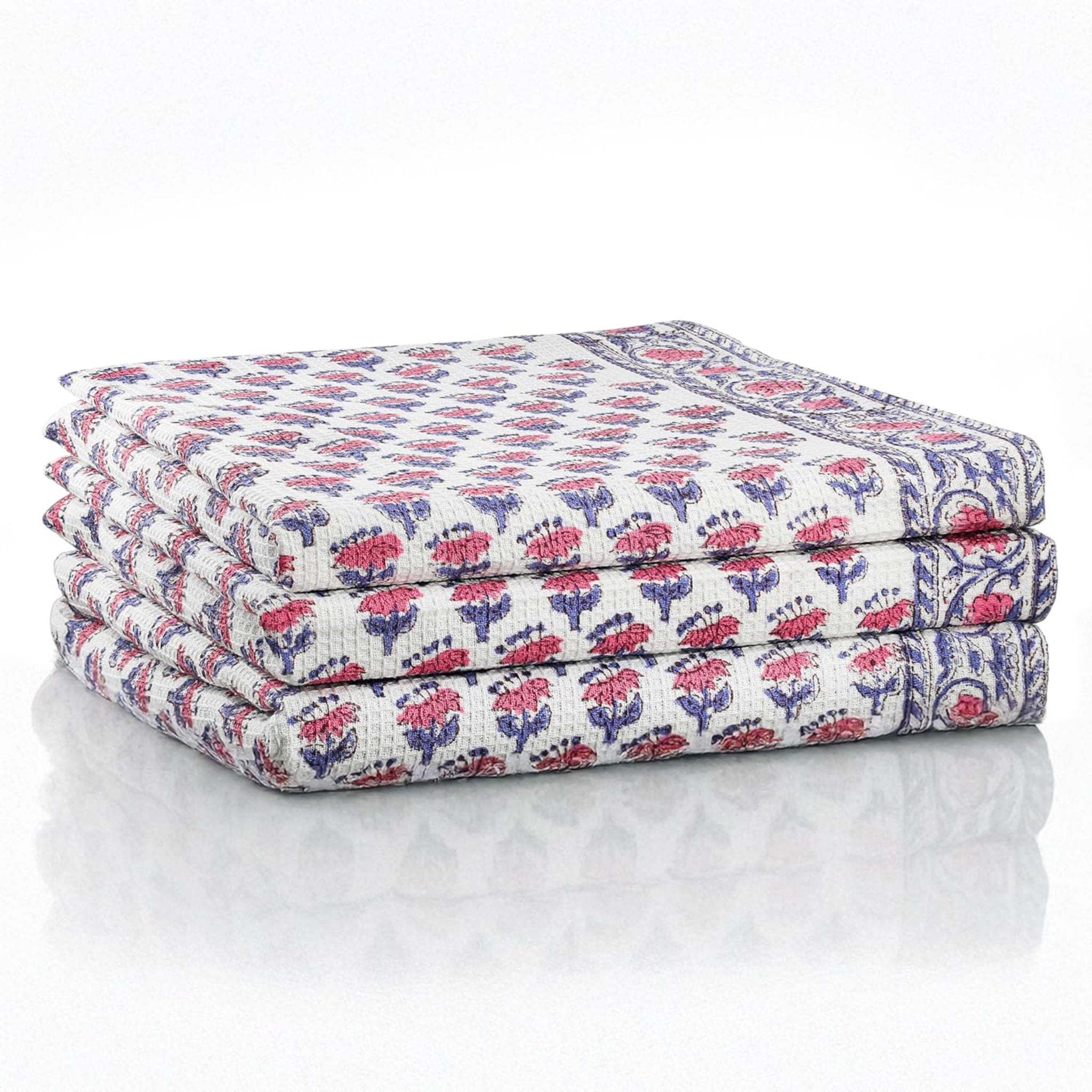 Set of three folded pink waffle cotton towels with floral hand block print

