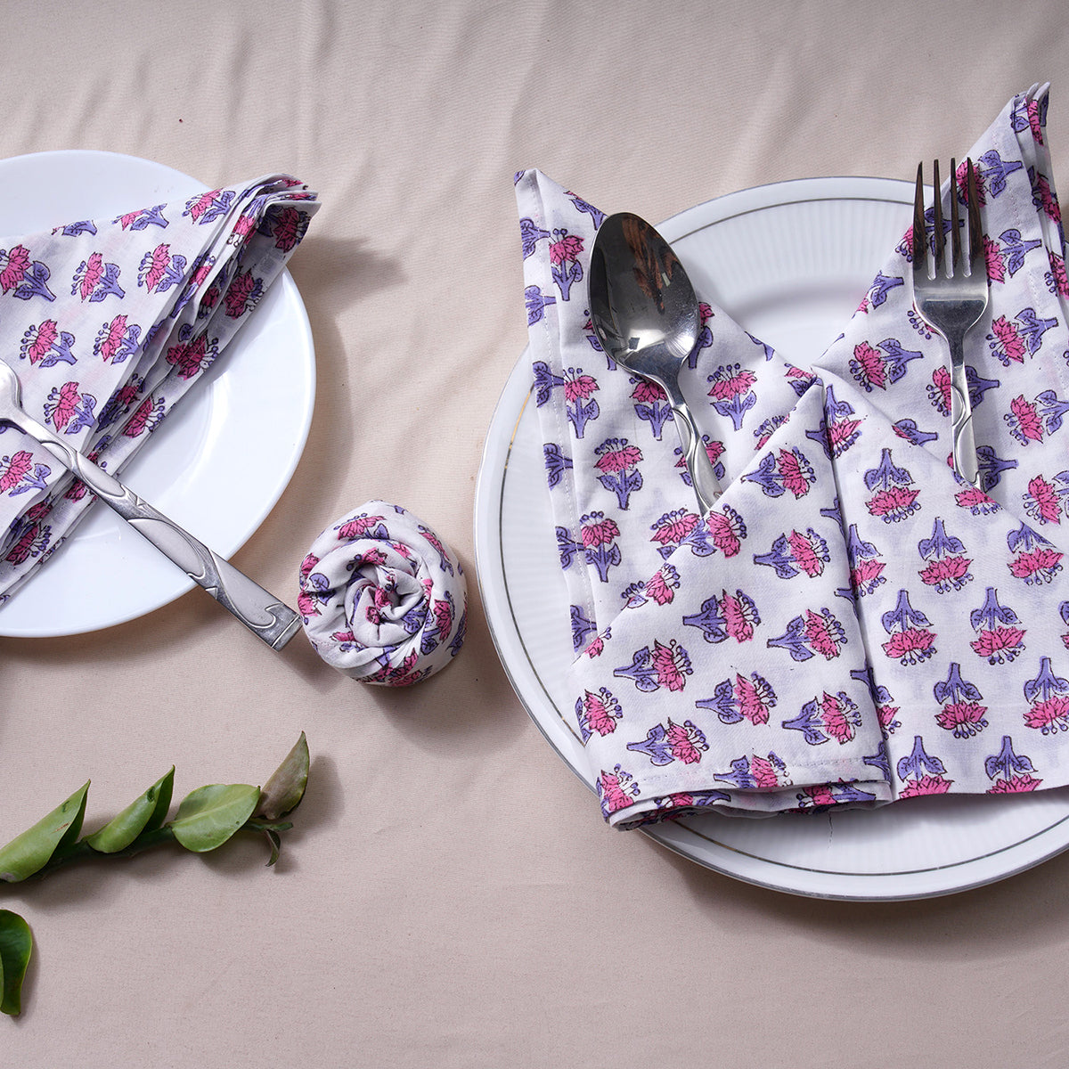 Two rolled floral napkins styled vertically on a white plate.