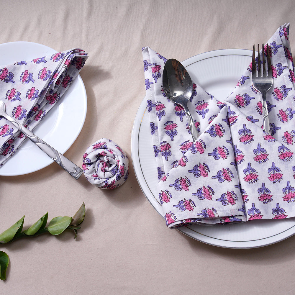 Two rolled floral napkins styled vertically on a white plate.