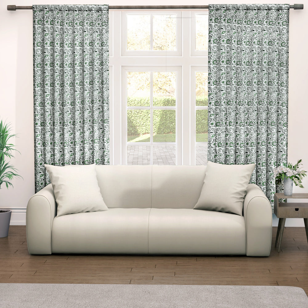 Semi-sheer cotton block print curtains in green, hanging in a room with a light filtering through, showcasing a boho-chic style.