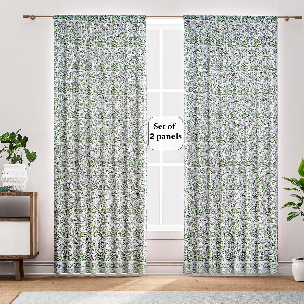 Semi-sheer cotton block print curtains in green, hanging in a room with a light filtering through, showcasing a boho-chic style.