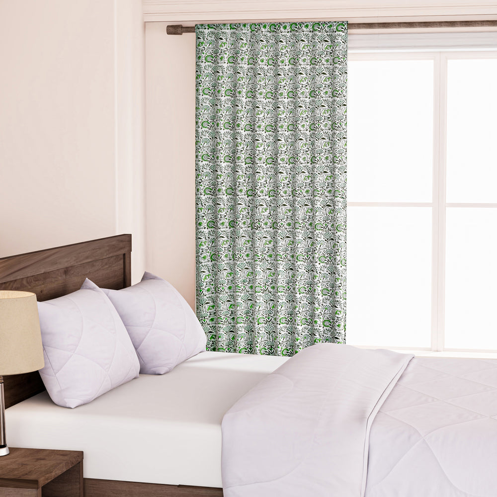 Semi-sheer cotton block print curtains in green, hanging in a room with a light filtering through, showcasing a boho-chic style.