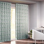 Semi-sheer cotton block print curtains in green, hanging in a room with a light filtering through, showcasing a boho-chic style.