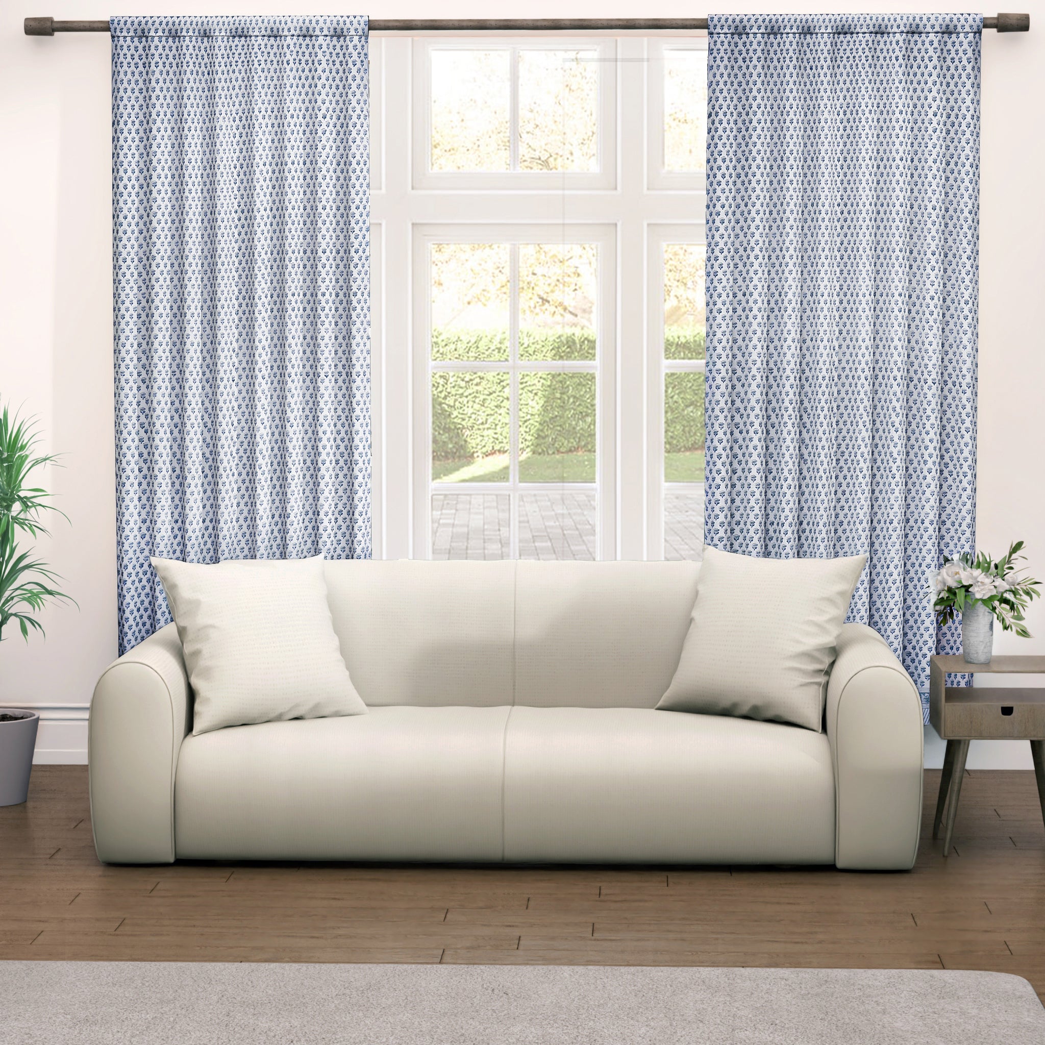 A pair of semi-sheer blue cotton block print curtains hanging in a room with a light coming through, showcasing a boho-chic design.