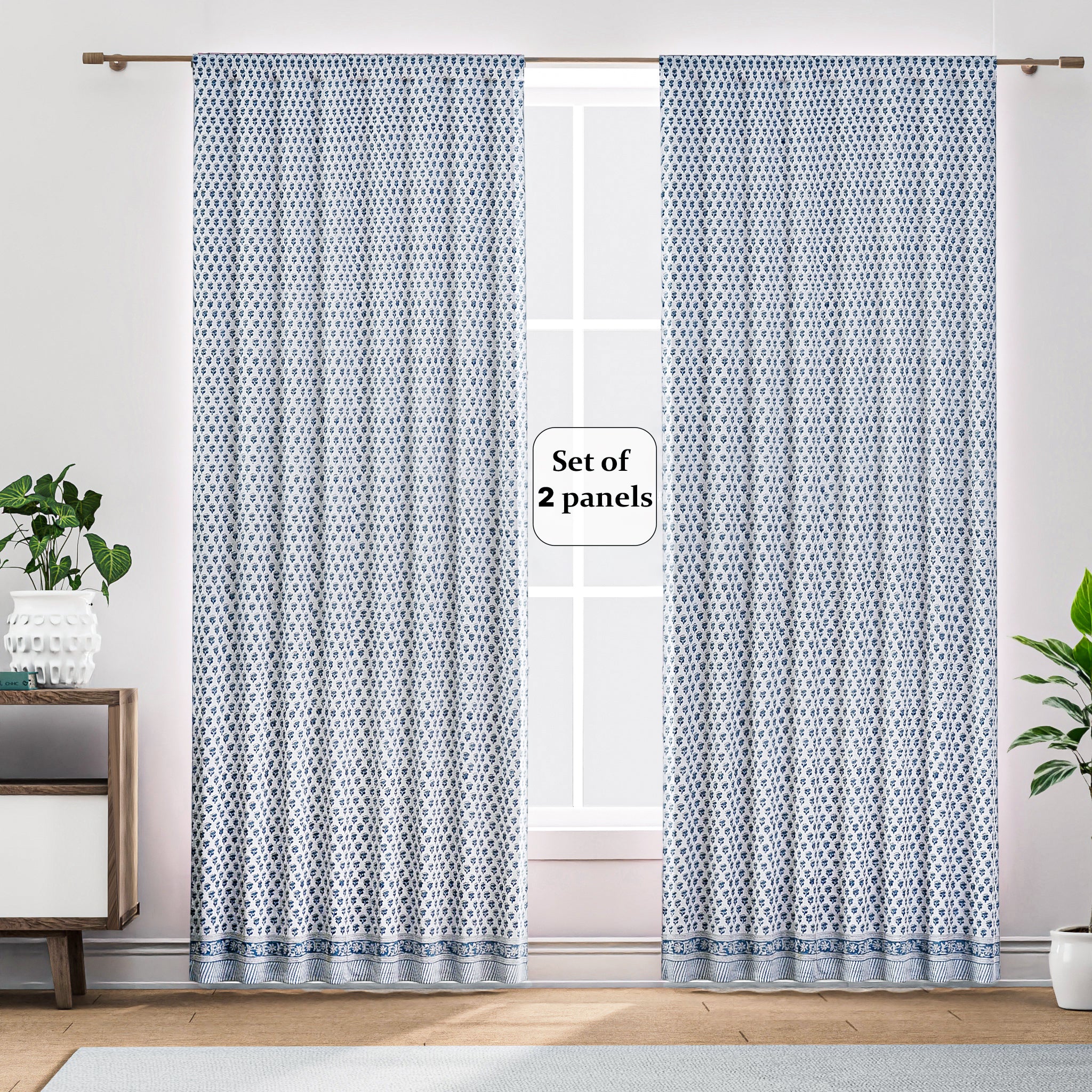 A pair of semi-sheer blue cotton block print curtains hanging in a room with a light coming through, showcasing a boho-chic design.