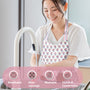 lady washing dishes and wearing a pink and white floral block print apron thats breathable, has wide coverage, washable, and stylish and comfortable