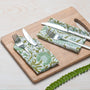 green floral napkin placed under silverware on wooden serving tray, with matching napkins rolled beside